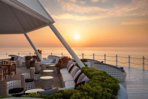 a patio with tables and chairs and the ocean at sunset at Paloma Foresta in Beldibi