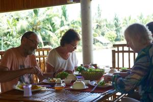 Eine Gruppe von Menschen, die an einem Tisch sitzen und Essen essen. in der Unterkunft Tra Vinh Lodge in Nguyệt Hạng