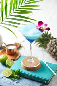 uma bebida azul num copo de martini num livro em Mayson Place Hotel em Ban Phraek Sa