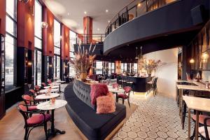 a woman sitting on a couch in a restaurant at Van der Valk TheaterHotel De Oranjerie in Roermond