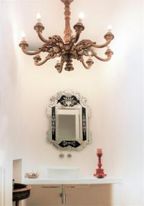 un lampadario pendente appeso a un lavandino del bagno con specchio di Reggia del Saraceno a Siracusa