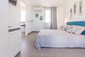 a white bedroom with a large bed and a kitchen at B&B Naracheddu Elite in Santa Teresa Gallura