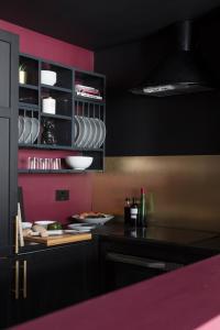 a kitchen with black cabinets and a pink wall at Luxury Boutique Apt in fashionable Stockbridge 5* in Edinburgh
