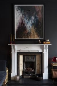 einen Kamin mit einem Gemälde darüber im Wohnzimmer in der Unterkunft Luxury Boutique Apt in fashionable Stockbridge 5* in Edinburgh