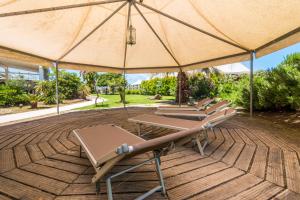 eine Gruppe von Liegestühlen und einem Sonnenschirm auf einer Terrasse in der Unterkunft B&B Le Dune - Self Check in in Lascari