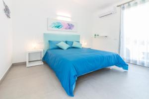 a white bedroom with a blue bed and a window at B&B Naracheddu Elite in Santa Teresa Gallura