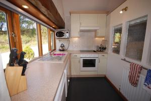 cocina con armarios blancos y encimera en Bowgie at Trewerry Cottages - Away from it all, close to everywhere en Newquay