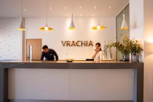 a man and woman sitting at a counter in a restaurant at Vrachia Beach Hotel & Suites - Adults Only in Paphos