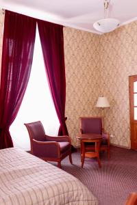 a bedroom with a bed and two chairs and a window at Pałac Brody in Brody