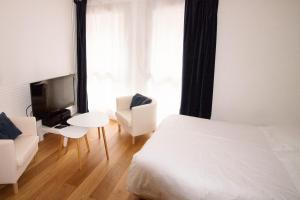 リールにあるStudioLille - Saint Michelのベッド2台、テレビ、椅子が備わるホテルルームです。