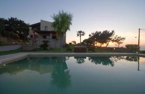 a swimming pool in front of a house with the sunset at Villa Russelia in Kalavárda