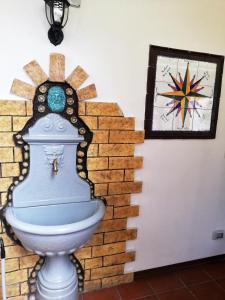 un bagno di fronte a un muro di mattoni con un quadro di Casa Vacanza NINA a Milazzo