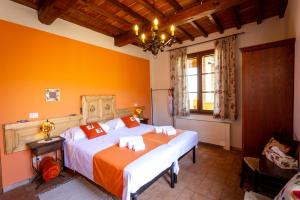 a bedroom with a large bed with an orange wall at Villa Amadeo by PosarelliVillas in Montaione +56 photos
