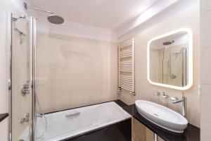 La salle de bains est pourvue d'une baignoire, d'un lavabo et d'une douche. dans l'établissement Beachfront Apartment Haga with Free Parking by Renters, à Sopot