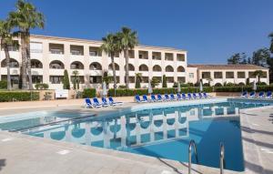 a pool with blue chairs in front of a building at Résidence Sognu Di Mare - Plage in Linguizzetta