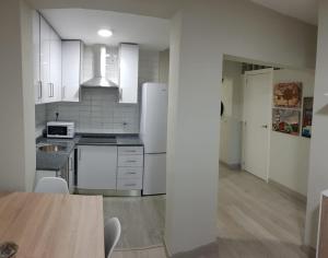 a kitchen with white appliances and a wooden table at Apartamento Barajas. Aeropuerto/Ifema in Madrid