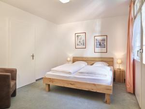 a bedroom with a bed with white sheets and a window at Hotel Tödi in Linthal