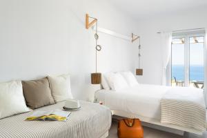 a white bedroom with two beds and a balcony at Gerofinikas Boutique Hotel in Apollonia