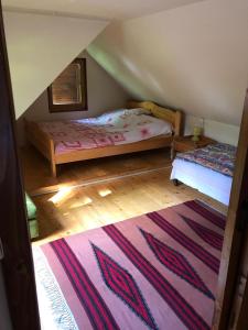 ヴラヒツァにあるForest Cottage Weekend Houseの屋根裏のベッドルーム(ベッド2台、ラグ付)
