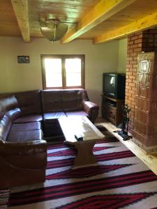un soggiorno con un divano in pelle e una TV di Forest Cottage Weekend House a Vlăhiţa
