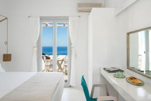 ein weißes Schlafzimmer mit einem Bett und einem Tisch mit einem Teller Essen in der Unterkunft Gerofinikas Boutique Hotel in Apollonia