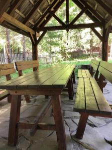 einem hölzernen Picknicktisch mit zwei Bänken in einem Pavillon in der Unterkunft Forest Cottage Weekend House in Vlăhiţa