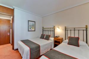 a hotel room with two beds and a table at Hotel Santillana in Santillana del Mar