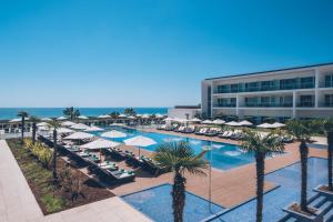 un complejo con una piscina con sombrillas y palmeras en Iberostar Selection Lagos Algarve, en Lagos