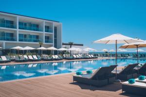 a swimming pool with chairs and umbrellas next to a building at Iberostar Selection Lagos Algarve in Lagos