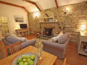 sala de estar con mesa y chimenea de piedra en Dairy Cottage en Bodmin