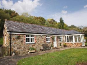 a stone house with a bench in front of it at Dairy Cottage in Bodmin