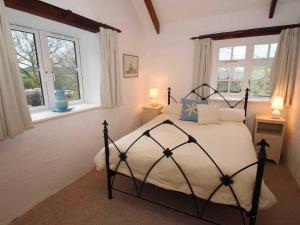 a bedroom with a bed and two windows at Dairy Cottage in Bodmin