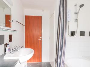 a bathroom with a sink and a wooden door at The Barn in Gunwalloe +16 photos