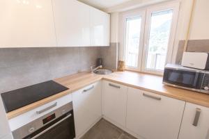 a kitchen with white cabinets and a microwave and a sink at Montreux & Leman View Apartment in Montreux