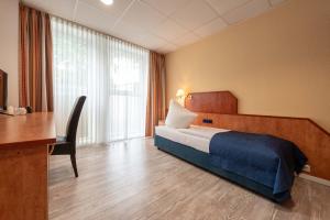 een hotelkamer met een bed en een bureau bij Boardinghouse Burgpark in Efferen