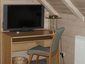 a computer desk with a television and a chair at Hotel Villa Sulmana in Neckarsulm