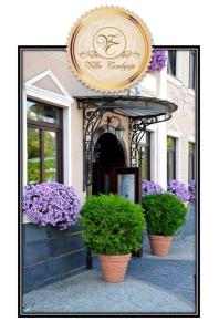 a building with purple flowers and plants in pots at Villa Tradycja in Białystok