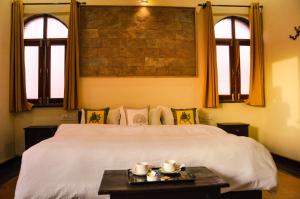 a bedroom with a large white bed and two windows at Hotel Vamdev Fort in Pushkar