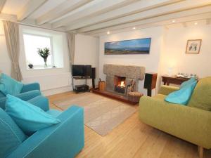 a living room with two blue couches and a fireplace at White Duck Cottage in Hayle