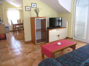 ein Wohnzimmer mit einem Sofa, einem TV und einem Tisch in der Unterkunft Apartments Kristina in Krk