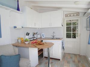 a kitchen with white cabinets and a table with fruit on it at Studio in Polperro