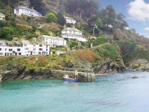a boat in a body of water with houses on a hill at Studio in Polperro