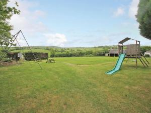 a playground with a slide and a bench in a field at Cider Cottage in Looe