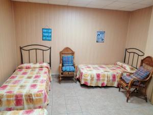 two beds and two chairs in a room at Albergue de Peregrinos A Santiago in Belorado
