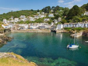 a boat in a body of water with houses at Cider Cottage in Looe
