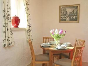 a table with chairs and a vase of flowers on it at Cider Cottage in Looe