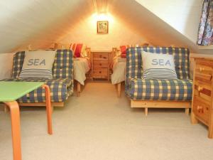 a attic room with two chairs and a bedroom at Cider Cottage in Looe