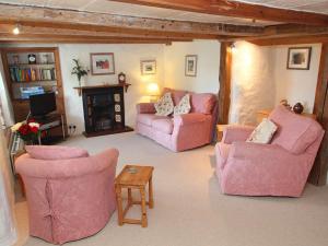 a living room with pink furniture and a fireplace at Rose Cottage in Helston
