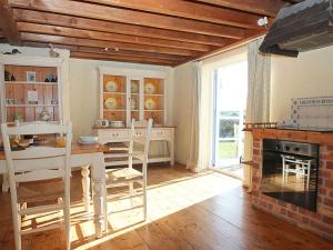 a kitchen with a table and chairs and a fireplace at Rose Cottage in Helston