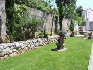 a garden with a stone wall and a vase of flowers at Apartments Kristina in Krk